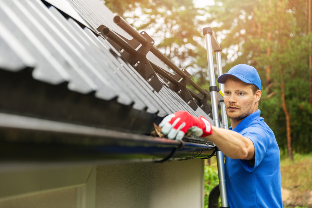 Worker,Cleaning,House,Gutter,From,Leaves,And,Dirt